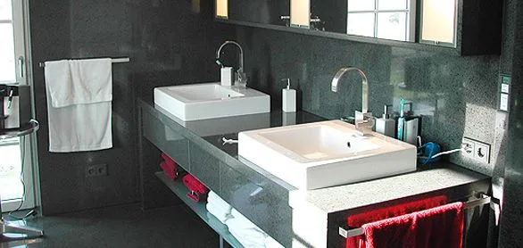 Bad mit dunkler Wandfläche, zwei Aufsatzbecken auf einer hellen Steinplatte und Spiegelschrank