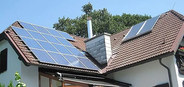 Wohnhaus mit Ziegeldach, großem Solarkollektorfeld und zwei weiteren Kollektoren neben dem Kamin